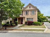 Charming brick home with a well-manicured lawn and a welcoming red front door at 4916 Gathering Pl, Suwanee, GA 30024