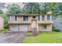 Charming split-level home with a two-car garage, light siding, and a welcoming front yard and stairwell at 2218 Lowtrail Ct, Lithonia, GA 30058