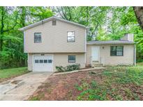 Two-story home with beige siding and a single-car garage in wooded setting at 5218 Tina Ct, Stone Mountain, GA 30083