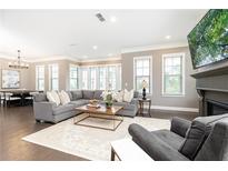 Bright living room features a cozy gray sectional, modern fireplace, and hardwood flooring at 3900 Danube Ln, Atlanta, GA 30339