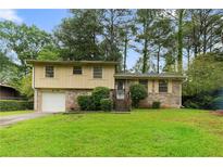 Charming split-level home with a well-maintained lawn, brick accents, and a one-car garage at 6535 Buckhurst Trl, Atlanta, GA 30349