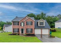 Traditional two-story brick home with a two-car garage, black shutters and landscaped front yard at 6683 Princeton Park Ct, Lithonia, GA 30058