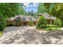 Charming home featuring a circular driveway, mature trees, and lush landscaping creating a private oasis at 4161 Thunderbird Se Dr, Marietta, GA 30067