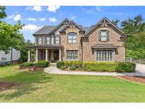 Beautiful stone and brick home with a manicured lawn, established bushes, and three-car garage at 6625 Baywood Run, Cumming, GA 30041