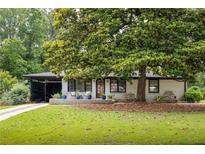 Charming single-story home features a mature tree and a well-manicured front lawn at 1195 Russell Dr, Decatur, GA 30030