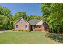 Charming brick home featuring a well-manicured lawn, mature trees, and inviting curb appeal at 160 Vinnys Way, Covington, GA 30014