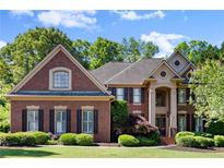 A classic brick home featuring a manicured lawn and lush landscaping, embodying suburban elegance at 1860 Hill Chase, Alpharetta, GA 30022