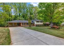 Charming home featuring a well-maintained lawn, mature trees, and a convenient covered parking area at 2921 Country Squire Ln, Decatur, GA 30033