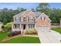 Charming brick two-story home with a welcoming front porch and a well-manicured lawn at 927 Ivey Chase Pl, Dacula, GA 30019