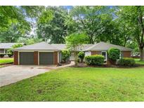 Charming brick home featuring a two-car garage, inviting entrance, and manicured lawn at 215 Truehedge Trce, Roswell, GA 30076