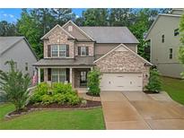 Charming two-story home with brick facade, covered front porch, two-car garage, and lush landscaping at 267 Snow Owl Way, Lawrenceville, GA 30044