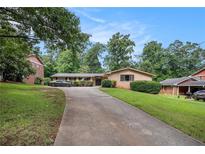 Ranch style home featuring a long driveway, brick facade, manicured shrubs, and mature trees at 3946 Flakes Mill Rd, Decatur, GA 30034