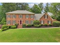 Charming brick home featuring a well-manicured lawn, mature trees, and traditional shutters at 5545 Durrett Dr, Atlanta, GA 30338