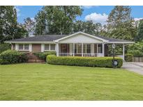 Charming brick home with a well-manicured lawn, trimmed hedges and a covered porch at 4125 Lindsey Dr, Decatur, GA 30035
