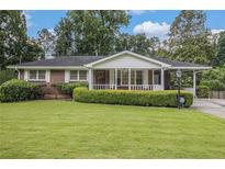 Charming brick home featuring a well-manicured lawn and a covered front porch at 4125 Lindsey Dr, Decatur, GA 30035
