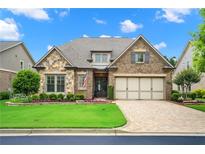 Charming single-Gathering home boasts a manicured lawn, stone accents, and a two-car garage at 2115 Creekstone Point Dr, Cumming, GA 30041