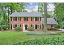 Charming two-story brick home featuring a well-manicured lawn and mature trees at 3564 Liberty Ln, Marietta, GA 30062