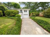 Charming white house with well-manicured lawn and garden, driveway, and a convenient one-car garage at 80 Vinson Se Dr, Atlanta, GA 30317
