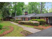 Charming brick home with a landscaped front yard featuring mature trees and colorful azaleas at 302 Chinquapin Sw Dr, Marietta, GA 30064