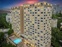 Exterior view of a high-rise condo building with a pool, surrounded by trees and other buildings at 2479 Peachtree Ne Rd # 305, Atlanta, GA 30305