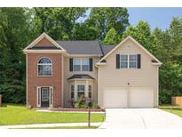 Charming two-story home featuring a manicured lawn, brick accents, and a two-car garage at 4608 Treasure Ct, Forest Park, GA 30297