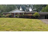 Charming brick home with a covered porch and carport, nestled in a lush green yard with mature trees at 4889 Fairforest Dr, Stone Mountain, GA 30088
