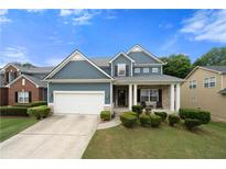 Charming home with a manicured lawn, featuring blue siding and a two-car garage at 1536 Fenmore St, Lithia Springs, GA 30122