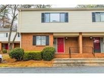 Two-story townhouse with brick facade, tan siding, black shutters, and a vibrant red front door for eye-catching curb appeal at 3312 Northcrest Rd # A, Atlanta, GA 30340
