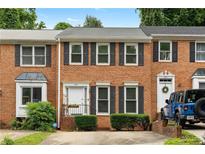 Charming brick townhome featuring black shutters, trimmed bushes and a white door with black handrails and a flower pot at 2779 Bentley Se Pl, Marietta, GA 30067