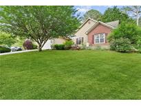 Charming home featuring a lush green lawn and mature trees at 117 Laguna Springs Dr, Woodstock, GA 30188