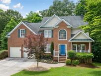 Charming brick two-story home with a well-manicured lawn, a blue front door and beautiful landscaping at 117 Willow View Ln, Canton, GA 30114