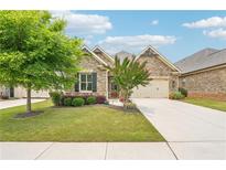 Charming brick home featuring a well-manicured lawn, landscaped garden beds, and a two-car garage at 332 Rosshandler Rd, Suwanee, GA 30024