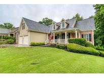 Charming home with a manicured lawn, complemented by a welcoming front porch and an American flag waving proudly at 403 Hidden Hills Ct, Canton, GA 30115