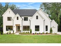 Charming white brick home featuring black trim, a well-manicured lawn, and lush landscaping at 4757 Lake Forrest Drive Northwest Dr, Atlanta, GA 30342