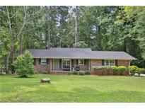 Charming brick ranch-style home featuring a well-manicured lawn and mature trees at 4774 Saint Bernard Sw Dr, Lilburn, GA 30047