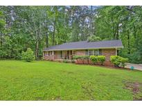 Charming brick ranch home featuring a well-manicured lawn and mature trees at 4774 Saint Bernard Sw Dr, Lilburn, GA 30047