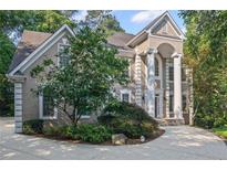 Elegant two-story home featuring a circular driveway, lush landscaping, and impressive columned entrance at 310 Ivy Brooke Ct, Atlanta, GA 30342