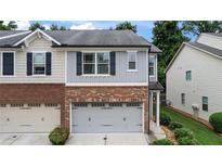 Two-story townhome featuring a brick and siding facade with an attached two-car garage at 147 Townview Dr, Woodstock, GA 30189