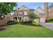 Beautiful brick home boasts an inviting front porch, manicured lawn, and attached two-car garage at 3250 Seven Oaks Dr, Cumming, GA 30041