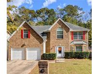 Charming brick home featuring a two-car garage, manicured lawn, and traditional architectural details at 4160 Post Oak Grv, Atlanta, GA 30349