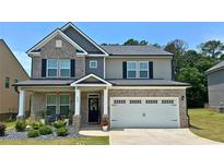 Charming two-story brick home boasts a well-manicured lawn, two car garage, and covered porch at 113 Canal St, Hampton, GA 30228