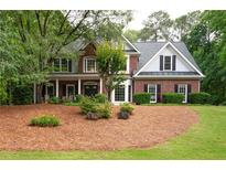 Charming brick home with lush landscaping, inviting front porch and a well-manicured lawn at 206 Kingsley Way, Woodstock, GA 30188