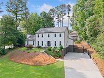 Charming white two-story home featuring manicured landscaping and a spacious driveway at 2885 Laurel Green Ct, Roswell, GA 30076