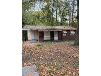 An exterior shot of a house with boarded up windows, a yard full of leaves, and a roof in need of repair at 711 Alfred Nw Rd, Atlanta, GA 30331