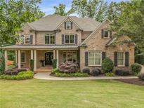 Charming brick home featuring manicured landscaping, a welcoming porch, and classic architectural details at 5605 Copper Creek Pass, Cumming, GA 30040