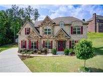 Beautiful two-story home featuring brick and stone exterior, red shutters, landscaped lawn, and mature trees at 332 Warwick Pl, Mcdonough, GA 30253