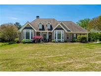 Beautiful brick home featuring a manicured lawn, complemented by decorative landscaping and large windows at 815 Spring View Ct, Covington, GA 30014