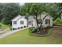 Charming home boasts a well-manicured lawn, complemented by classic black shutters and a pop of color from the front door at 3543 Pine Grove Dr, Douglasville, GA 30135