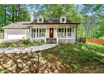 Charming home boasts a welcoming front porch, white siding, and a well-manicured front yard at 385 Russell Ridge Dr, Lawrenceville, GA 30043