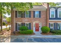 Charming two-story brick townhome featuring a red front door and manicured landscaping at 1 N Boundary Nw Pl, Atlanta, GA 30318